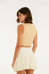 Top color beige, corte crop, con escote redondo y tirantes anchos.