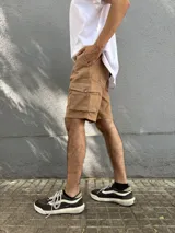 Bermuda de gabardina color marrón claro, corte recto, con bolsillos cargo laterales y bolsillos traseros con solapa.