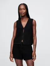 Chaleco negro de crochet con escote en V y cierre frontal con un botón.