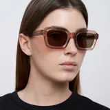 Lentes de sol cuadrados con armazón rosado transparente y lentes marrones polarizadas.