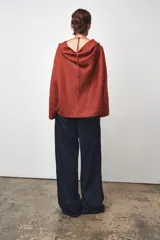 Blusa color ladrillo confeccionada en lino 100%. Tiene cuello fluido, mangas largas acampanadas y espalda descubierta ajustable con cordones.