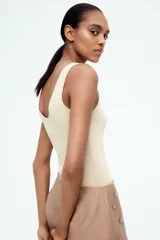 Musculosa de punto fino color beige, entallada, con escote en U en la parte delantera y trasera.