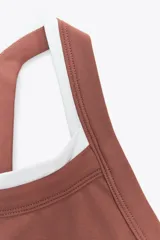 Top deportivo color ladrillo con escote redondo y tirantes blancos.