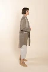 Camisa larga color beige con cuello mao, manga larga con tajo y botón. Diseño con bloques de tela con textura.
