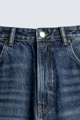 Pantalón de jeans de algodón, corte baggy fit, tiro medio, con efecto lavado en tonos grises y verdes. Presenta cinco bolsillos y cierre frontal con cremallera y botón.