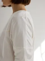 Remera blanca de algodón con corte holgado y costuras a la vista en color beige.