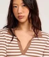 Blusa de punto con rayas horizontales marrones y blancas, cuello polo con escote en V y mangas largas.