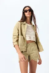 Sobrecamisa blanca de algodón con cuello camisero, botones marrones y detalles de encaje calado en el ruedo.