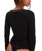 Top de manga larga ajustado de punto ligero tipo pointelle, color blanco, con escote en V ribeteado con encaje negro y blanco.