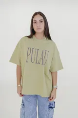 Remera verde con estampado de la palabra "Pulau" en color lila.