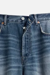 Pantalón de jean celeste con efecto lavado, corte flare fit y caída baggy desde la rodilla hasta el tobillo. Tiene cinco bolsillos y cierre frontal con botones.