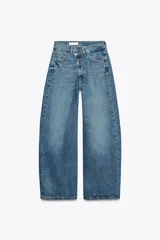 Jeans de tiro medio color azul denim, corte baggy, con trabillas y cinco bolsillos. Cierre frontal asimétrico con cremallera y botones metálicos.