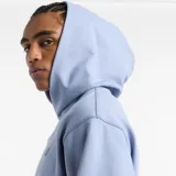 Canguro celeste de corte holgado con capucha y bolsillo tipo canguro. Logo de New Balance bordado en el pecho.