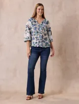 Blusa estampada con flores azules y verdes, cuello a la base con escote en V y volados. Manga larga con puño y apliques de puntilla.