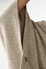 Capa con cuello, cierre frontal con botones y bolsillos delanteros. Confeccionada en lana fina sin teñir, diseñada exclusivamente por Don Baez.