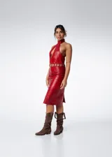 Vestido midi rojo de cuero con cuello halter, abertura en el pecho, cinturón de aros dorados y cierre lateral con cremallera.