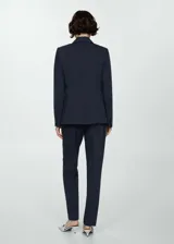 Blazer azul marino de corte entallado, con cuello de solapa de muesca, manga larga, hombros estructurados, dos bolsillos de ribete en la parte delantera, detalle de pinzas, abertura posterior y forro interior.