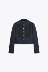 Chaqueta corta azul marino de lana con cuello redondo, manga larga con abertura y botones, detalle de alamares negros en el delantero, forro interior y cierre frontal con botones metálicos en relieve.