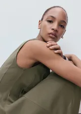 Vestido corto color verde militar, sin mangas, con cuello barco y falda evasé con pliegues.