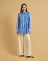 Camisa celeste holgada de manga larga con bolsillo en el pecho y cuello clásico.