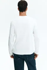 Remera blanca de algodón de manga larga con cuello redondo.