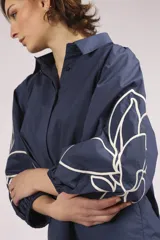 Camisa azul marino con bordados de flores blancas en mangas y ruedo.