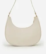 Cartera tipo baguette color beige, confeccionada en PU con acabado liso. Cuenta con cierre de cremallera y metales en tono dorado claro. El asa es ajustable y tiene un espacio interno ideal para el uso diario.