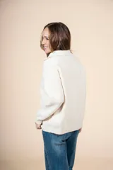 Cardigan color crudo de tejido de punto acanalado, con cuello alto y cierre frontal parcial con cremallera metálica. De corte oversize, mangas largas y puños ajustados.