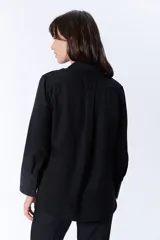 Camisa negra de manga larga con cuello clásico y cierre frontal con botones.