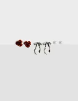 Set de tres pares de aros pasantes con cierre de tope a presión: un par de aros con forma de rosa color rojo óxido, un par de aros con forma de moño plateado y un par de aros con forma de perla blanca.