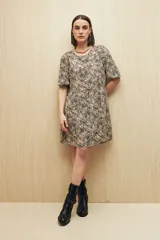 Vestido corto con estampado animal print en tonos beige, negro y marrón. Tiene corte holgado, mangas cortas y falda con vuelo.