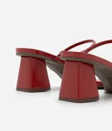 Sandalias mule rojas de material sintético con punta cuadrada, tiras finas, detalle de dedera con adorno dorado y tacón bloque mediano.