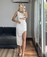 Vestido midi negro con corte asimétrico, una manga, abertura lateral y frunce en la cintura.
