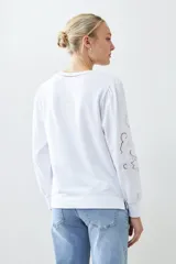 Sweatshirt rojo de manga larga con cuello redondo y calados bordados en los hombros y mangas.