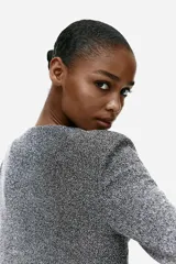 Saco corto de punto color gris jaspeado, con cuello redondo, cierre frontal con botones metálicos y bolsillos de parche decorativos.