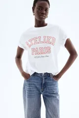 Remera blanca de algodón con estampado rojo que dice "Atelier Paris 115 Av. France, Paris".