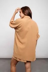 Camisa larga color beige con botones y cuello.