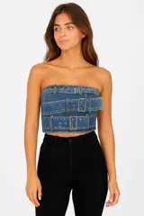 Top strapless de jean azul con tres tiras horizontales con hebillas plateadas.