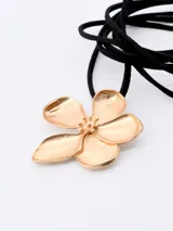 Gargantilla choker con cordón fino de terciopelo negro y dije de flor dorada.