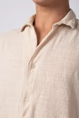 Camisa de lino color blanco, de manga corta, con cuello clásico y cierre frontal con botones.