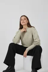 Sweater acrílico color natural, con cuello redondo, diseño de fantasía y corte ajustado al cuerpo. Presenta mangas largas abullonadas con detalles de punto en relieve.