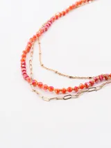Collar dorado con cuentas multicolor en tonos rojos y anaranjados, diseño elegante y ligero.