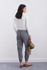 Pantalón de corderoy gris, de corte holgado, con elástico en la cintura, cierre y botón. Tiene bolsillos aplicados en el delantero y puños de piernas con elástico interno.