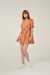 Vestido corto color naranja con estampado floral multicolor, de corte holgado y mangas cortas con volados.
