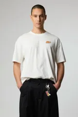 Remera blanca de algodón con cuello redondo y manga corta. Estampado pequeño en el pecho con el logo de la marca Blue Banana en color naranja.