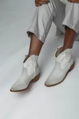 Botines de cuero color gris claro, estilo texano, con puntera fina, caña baja y taco de madera.