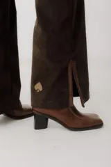 Pantalón de pana marrón con corte acampanado y abertura en el ruedo.