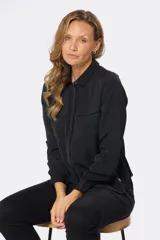 Blusa tipo camisa blanca con estampado de pequeñas flores negras, manga larga, botones nacarados ocultos con cartera y doble capa en el frente para evitar transparencias.