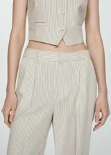 Pantalón largo de tiro alto con estampado de rayas verticales en tonos beige y gris. Tiene trabillas, dos bolsillos laterales y cierre frontal oculto con botón, gancho y cremallera.