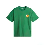 Remera de manga corta color verde, corte holgado (loose fit), con un pequeño parche circular estampado en el pecho con motivos naranjas y blancos.